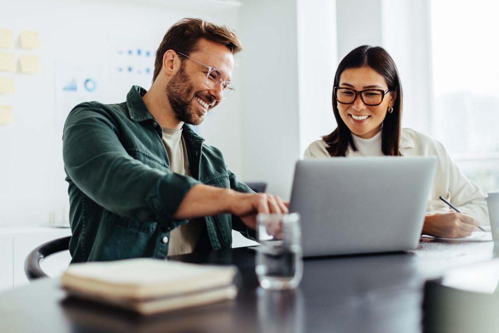 Two business people using a laptop together in an office